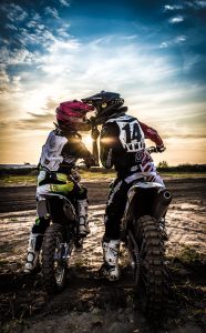 couple showing affection while sitting on separate dirt bikes