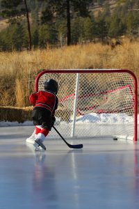 kid playing hockey on ice outside